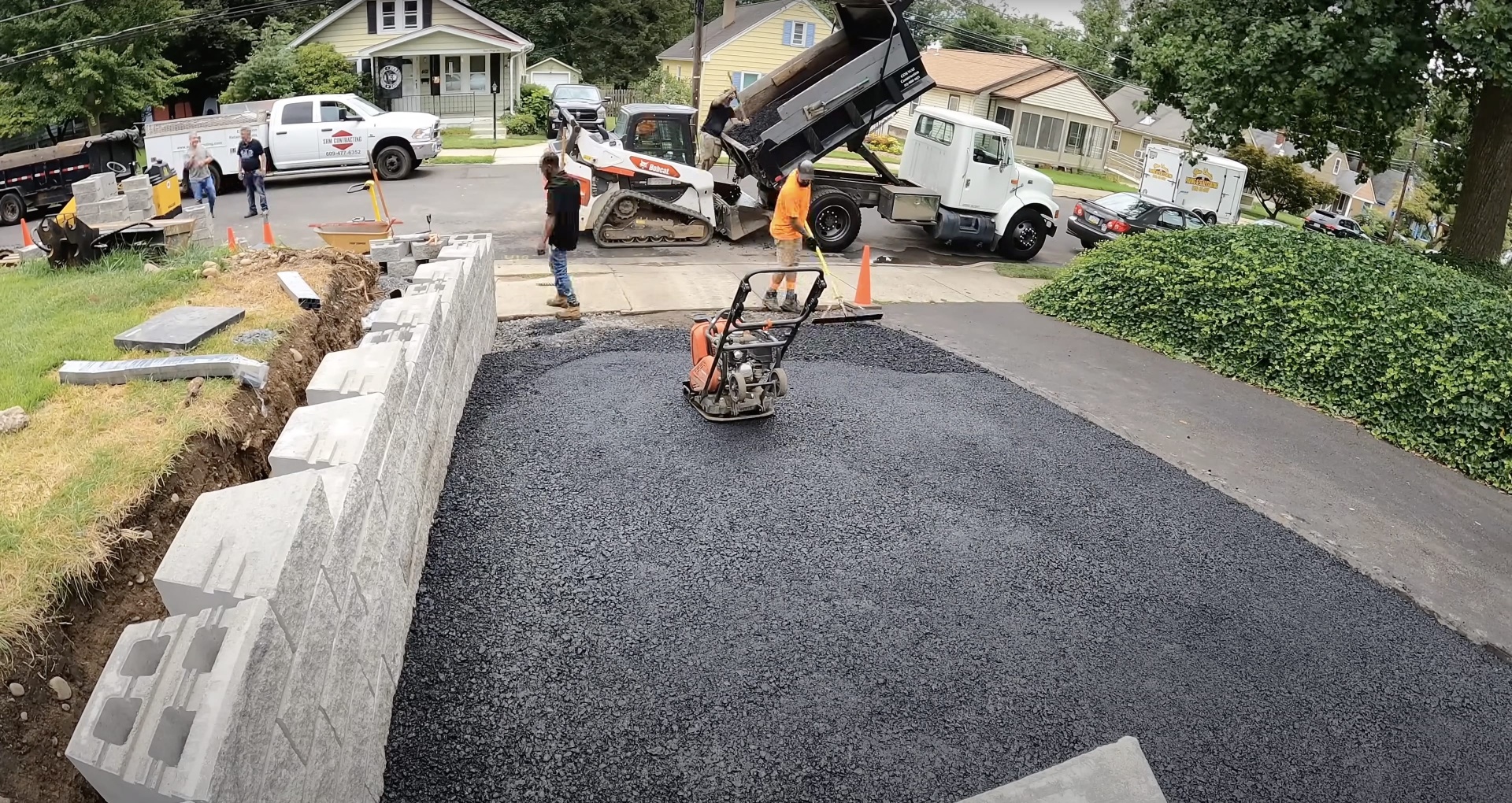 Complete driveway installation with concrete borders and proper drainage Professional asphalt driveway installation with concrete curbing and drainage